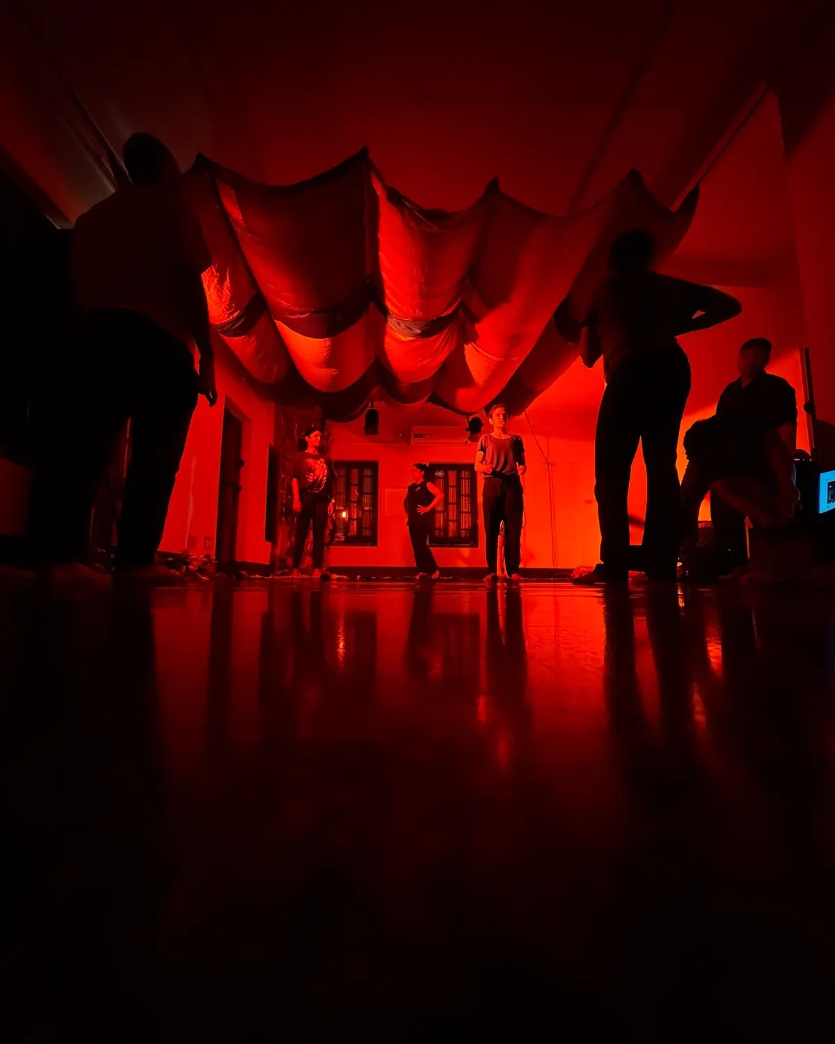 Dancers in silhouette under deep red light in the studio.