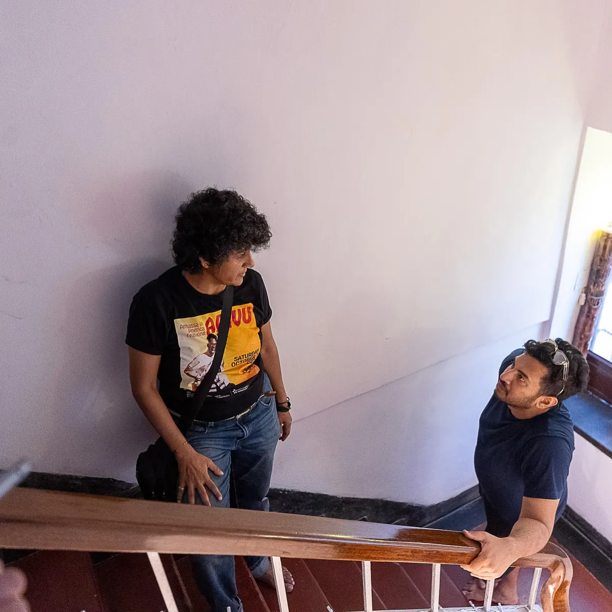 Two artists on the wooden stair, photographs pinned to the wall.
