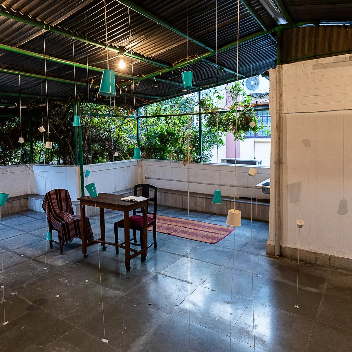 The covered terrace of the house with paper cups hanging on strings.